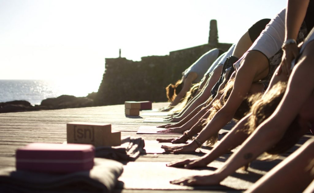 Herabschauender Hund im Yogakurs mit Meerausblick