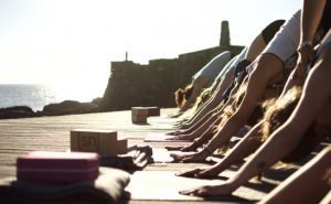 Herabschauender Hund im Yogakurs mit Meerausblick