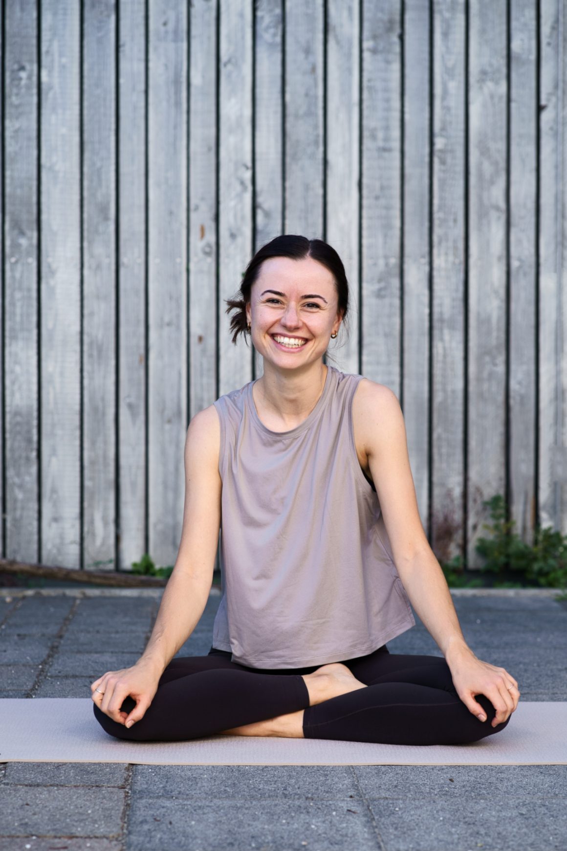 Yogalehrerin Janne im Lotussitz lachend auf der Matte