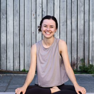 Yogalehrerin Janne im Lotussitz lachend auf der Matte